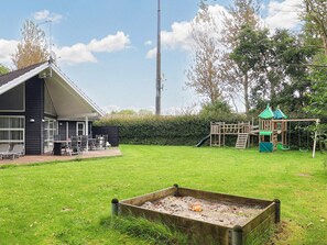 A house with a patio, a play structure, and a garden. - 10 Person Holiday Home in Vaeggerlose (Vaeggerlose)