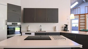 A modern kitchen with a central island, built-in oven, and a coffee machine. - 10 Person Holiday Home in Vaeggerlose (Vaeggerlose)