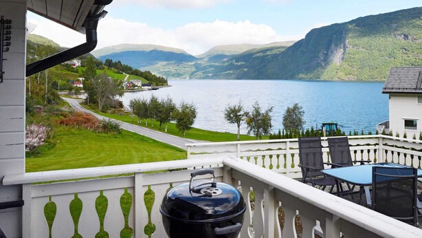 Un balcon avec vue sur un lac, un barbecue et du mobilier d’extérieur.