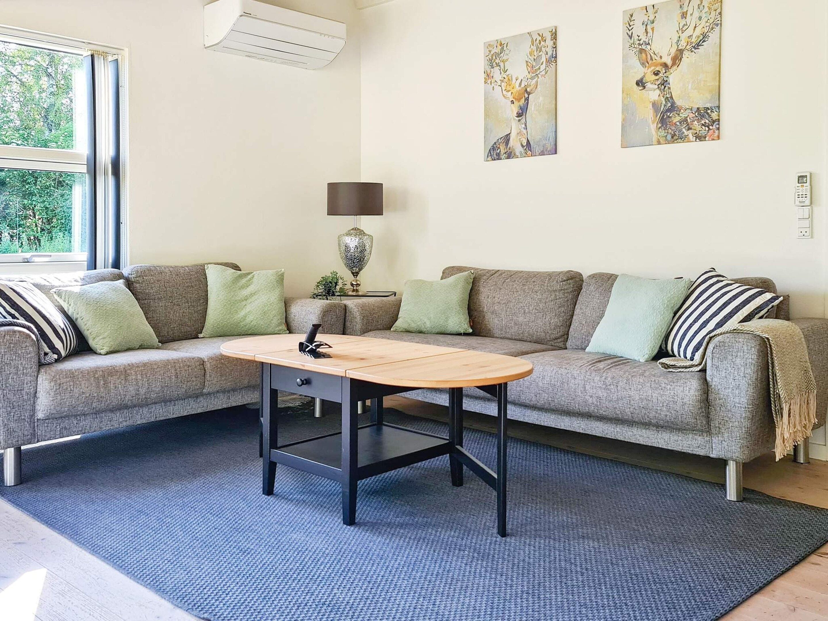 A living room with a grey sofa, a wooden coffee table, and two paintings on the wall.