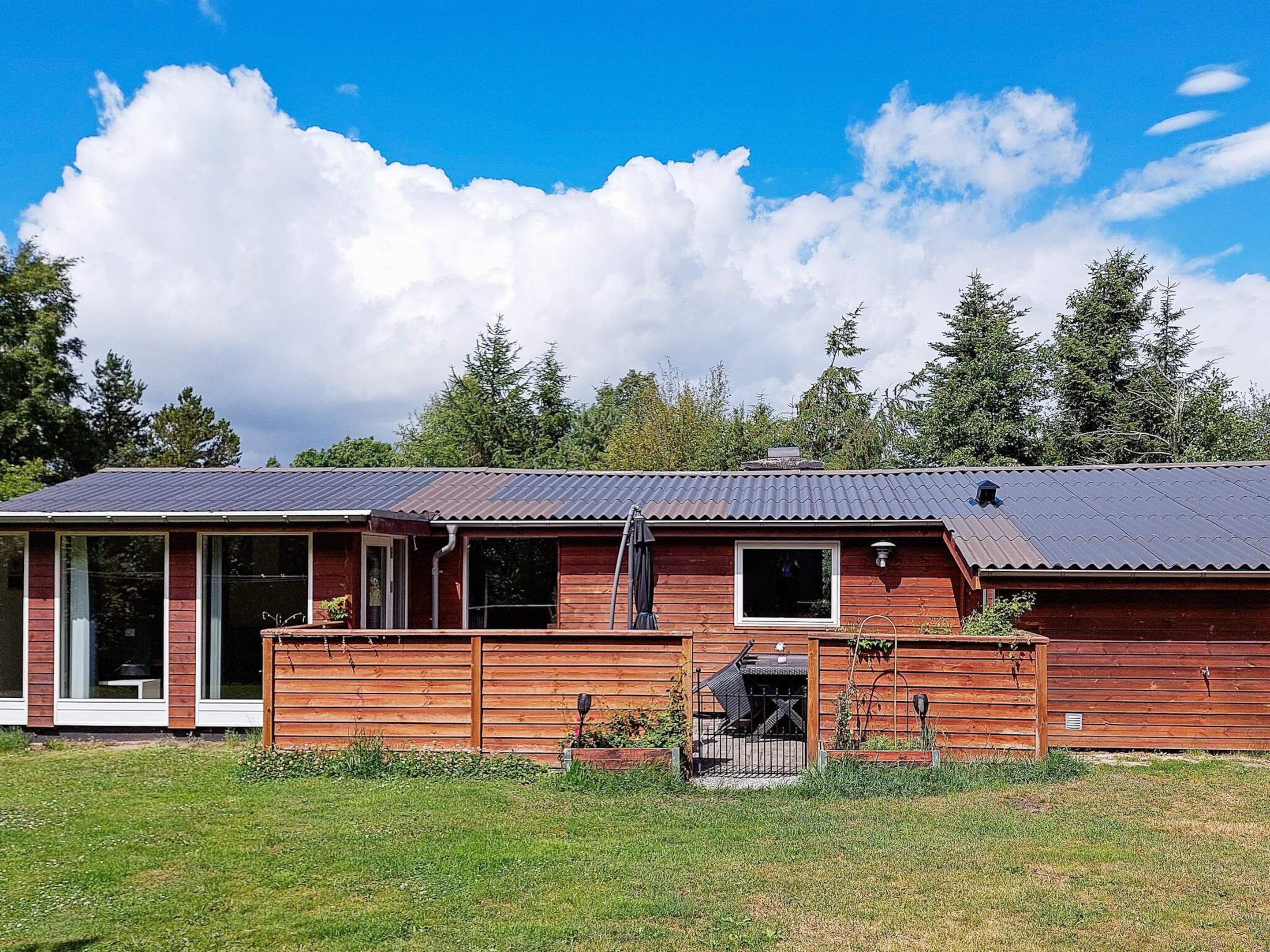 A two-story wooden house with a metal roof, large windows, and a covered porch.