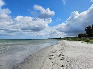 A beach with a sandy shore, calm water, and a partly cloudy sky. - 6 Person Holiday Home in Hals (Hals)