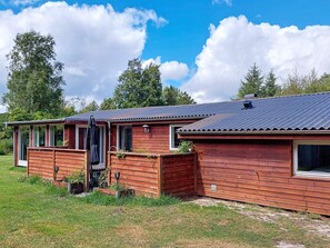 A wooden cabin with a metal roof, a front porch, and a small garden area. - 6 Person Holiday Home in Hals (Hals)