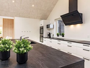 A modern kitchen with a dark countertop, white cabinetry, and a black range hood.