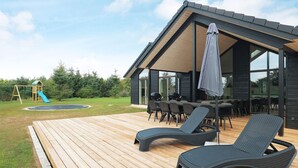 A modern outdoor deck with lounge chairs, a barbecue area, and a children's play structure. - 20 Person Holiday Home in Hojslev (Hojslev)
