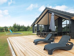 A modern outdoor deck with lounge chairs, a barbecue area, and a children's play structure. - 20 Person Holiday Home in Hojslev (Hojslev)