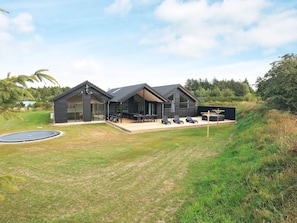 A modern two-story house with a covered patio area, a trampoline, and a well-maintained lawn. - 20 Person Holiday Home in Hojslev (Hojslev)