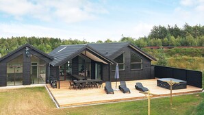 A modern house with a large deck, outdoor seating, and a view of the surrounding forest. - 20 Person Holiday Home in Hojslev (Hojslev)