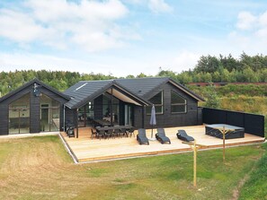 A modern house with a large deck, outdoor seating, and a view of the surrounding forest. - 20 Person Holiday Home in Hojslev (Hojslev)