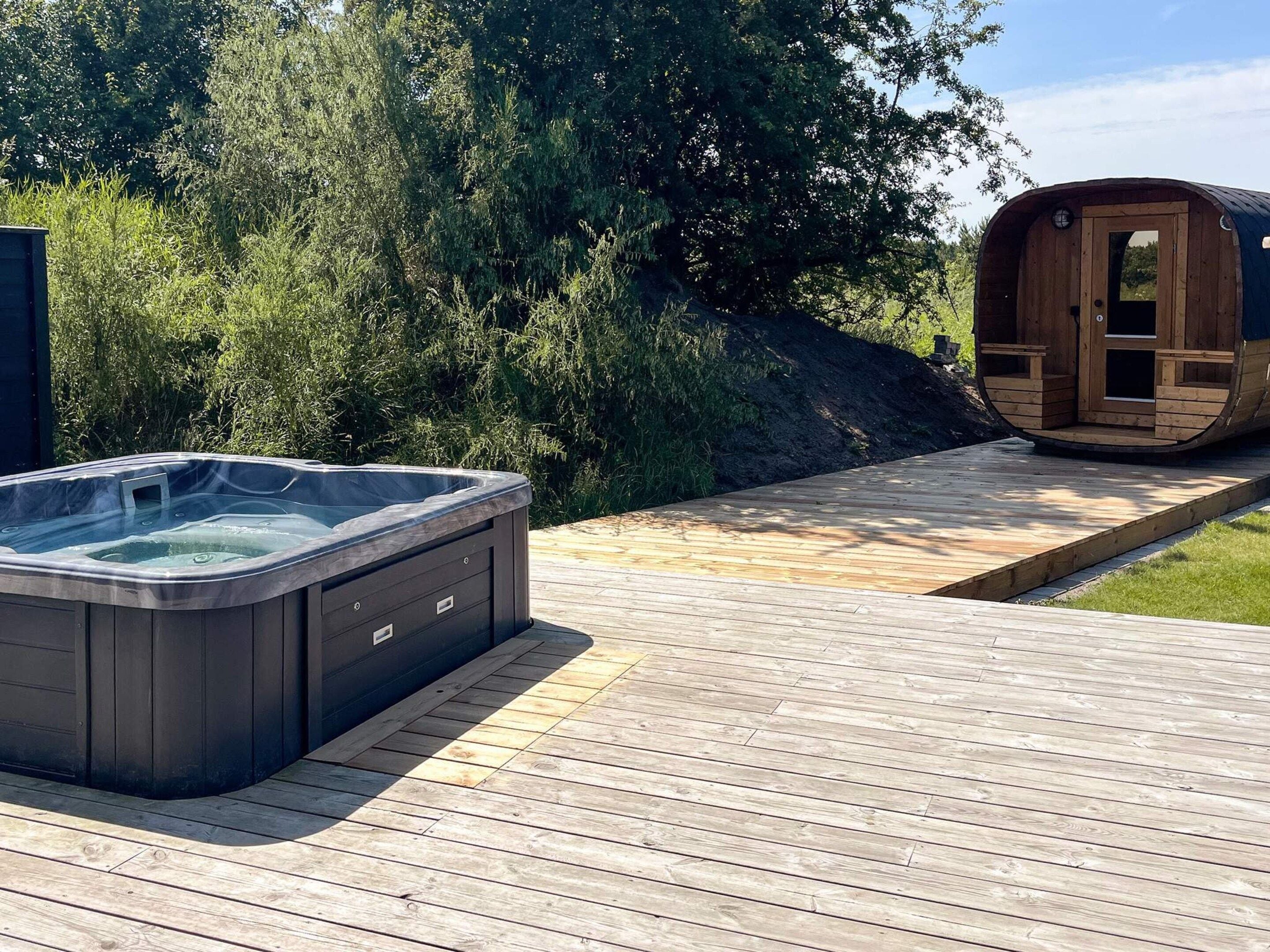 A hot tub and a sauna on a wooden deck with a natural backdrop.
