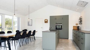 A modern kitchen with grey cabinetry, a central island, and a dining area with a table and chairs.