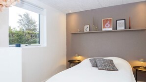 A bedroom with a bed, bedside tables, a window, and wall-mounted decor.