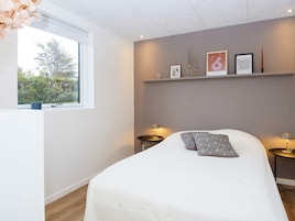 Un dormitorio con cama, mesitas de noche, una ventana y decoración en la pared.