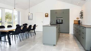 Una cocina moderna con armarios grises, una isla central y un comedor con mesa y sillas.