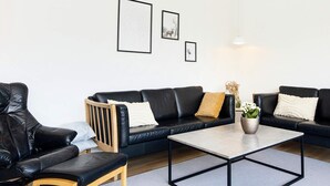 A modern living room with a black leather sofa, a wooden chair, and a coffee table.