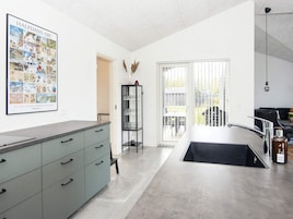 Una cocina moderna con una isla grande, un cartel enmarcado en la pared y vistas a través de la puerta de cristal.