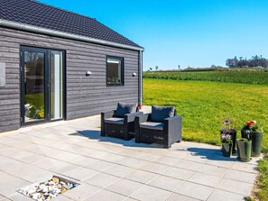 Une maison moderne dotée d’un patio aménagé avec des meubles d’extérieur et des plantes en pot.