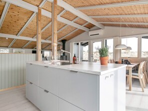 Una cocina moderna con una isla grande, vigas de madera en el techo y vistas al exterior.
