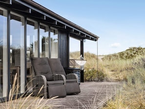 Un espace de détente extérieur moderne, doté d’un canapé et de fauteuils, d’un hamac suspendu et offrant une vue sur le paysage environnant.