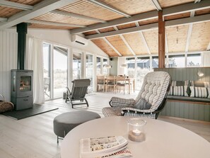 A modern interior with a wood-burning stove, a dining area, and a cozy seating arrangement.