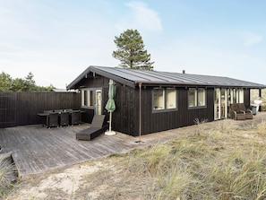 A modern black wooden house with a deck, outdoor seating, and a covered patio area. - 5 Star Holiday Home in Albaek (Aalbaek)