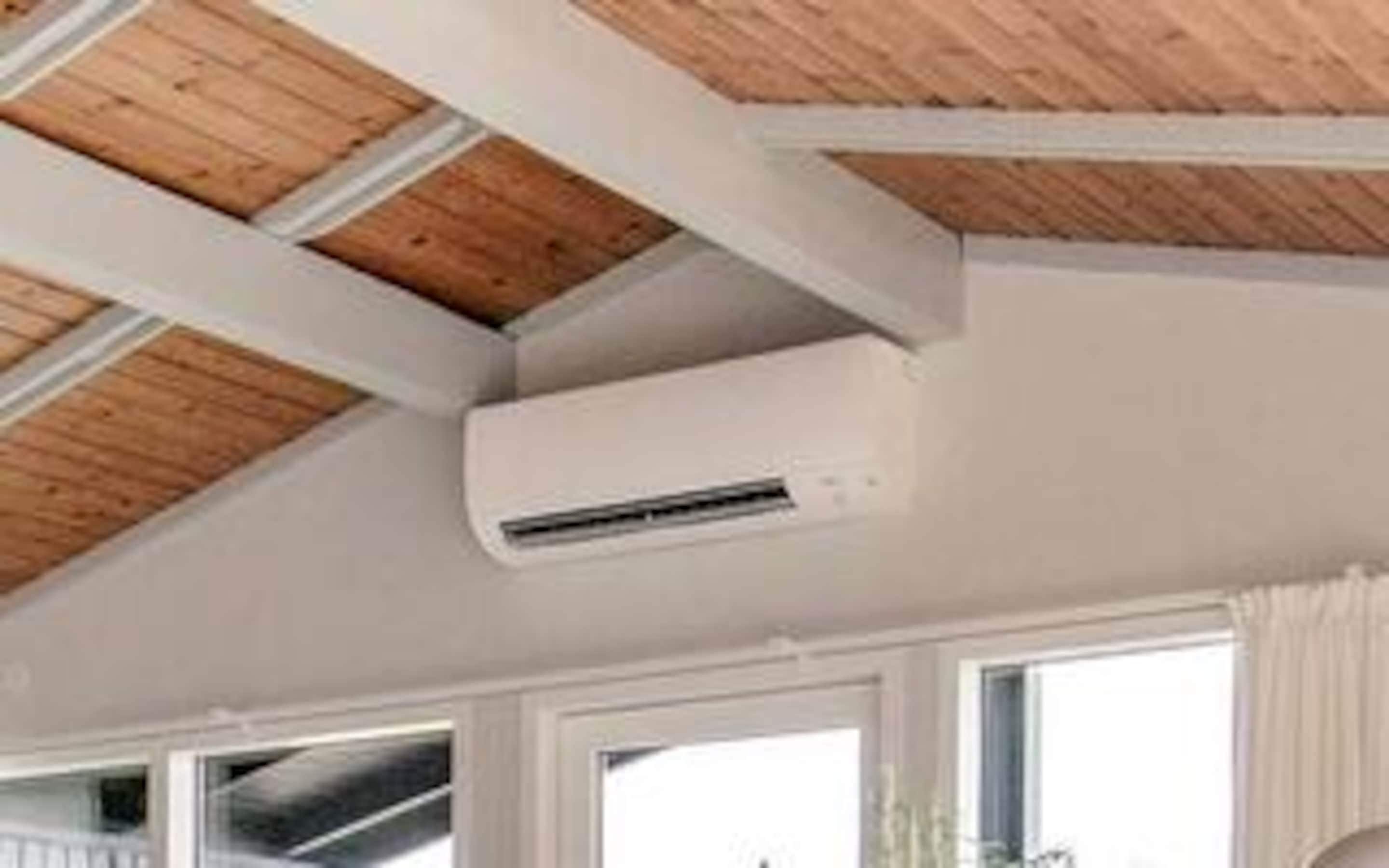 Una habitación con techo de madera, paredes blancas y un equipo de aire acondicionado.