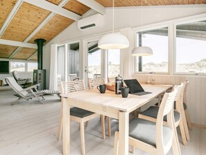 Een modern interieur met een houten eettafel, stoelen en een groot raam met uitzicht op de omgeving.