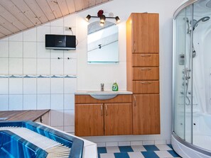 A bathroom with a shower, a sink with a mirror, and a wooden cabinet. - 8 Person Holiday Home in Tarm (Hemmet)