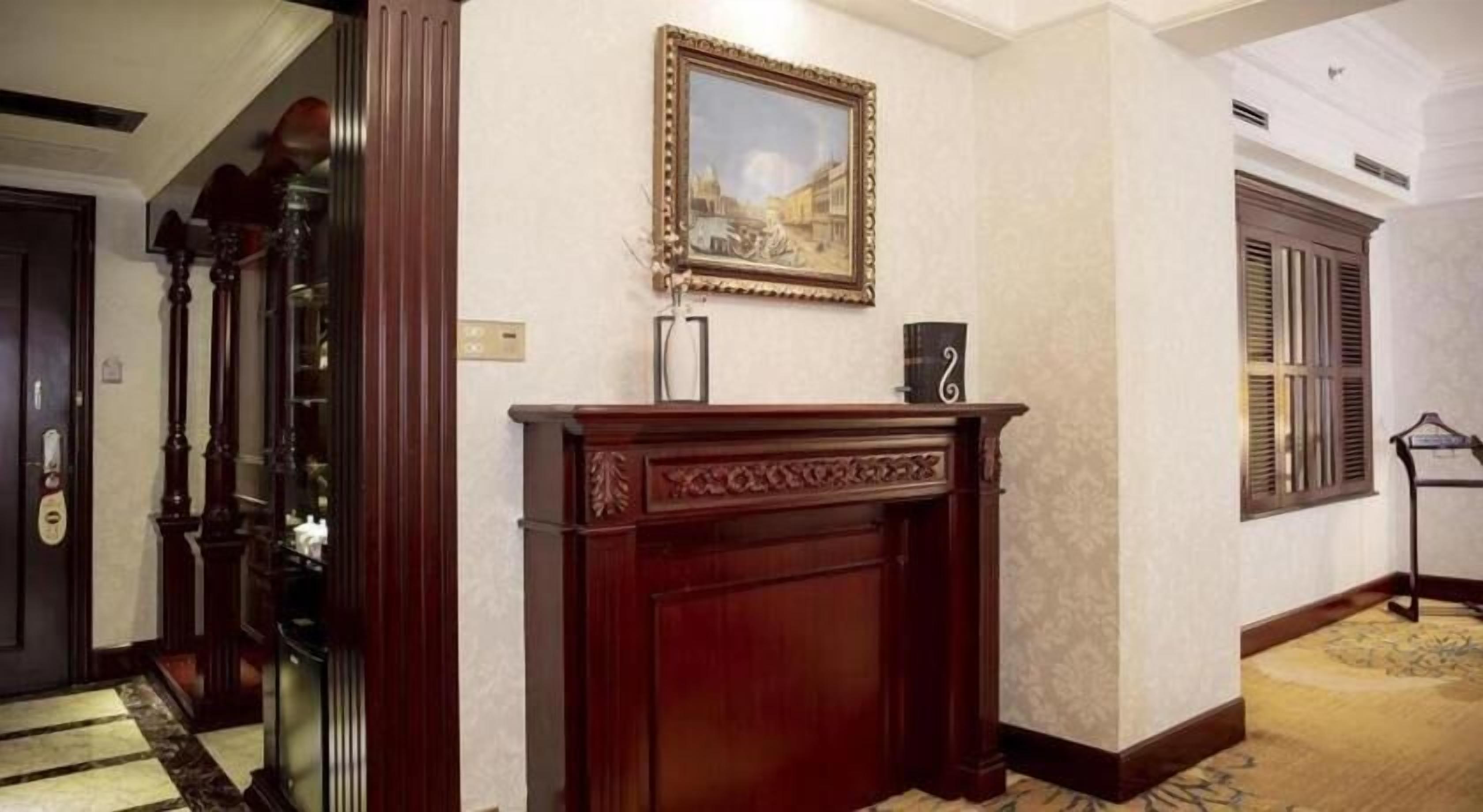 A hallway with a wooden fireplace, a framed picture above it, and a door with a handle.