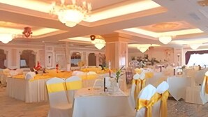 Une salle de banquet avec des tables rondes, des nappes blanches et des rubans jaunes.