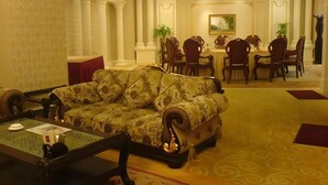 Un hall d’hôtel avec un canapé, un coin repas et un tableau accroché au mur.