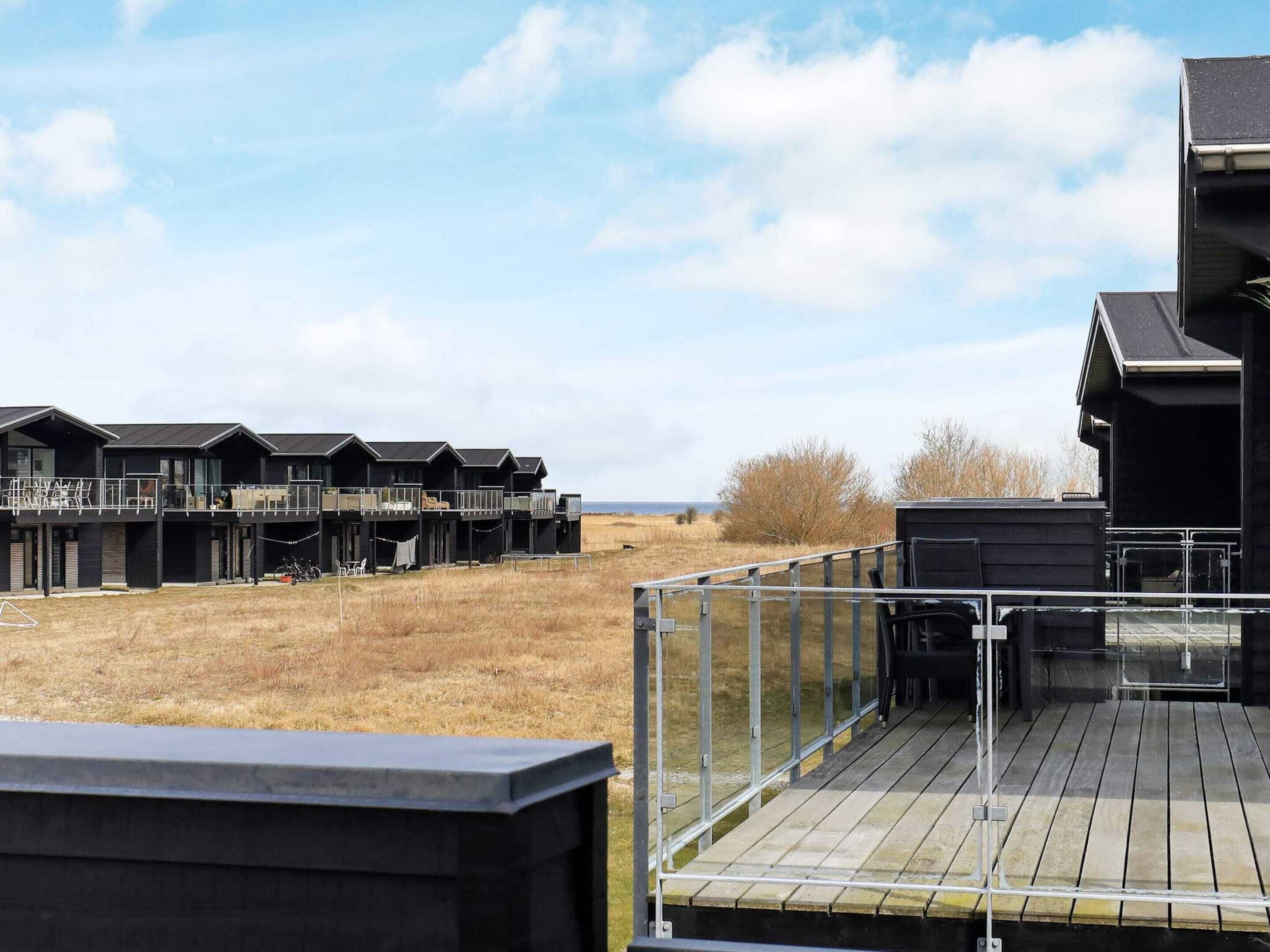 A modern building with multiple levels and balconies, overlooking a grassy field.