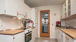 A modern kitchen with white cabinets, a wooden countertop, a built-in oven, and a coffee machine. - 6 Person Holiday Home in Pandrup (Pandrup)