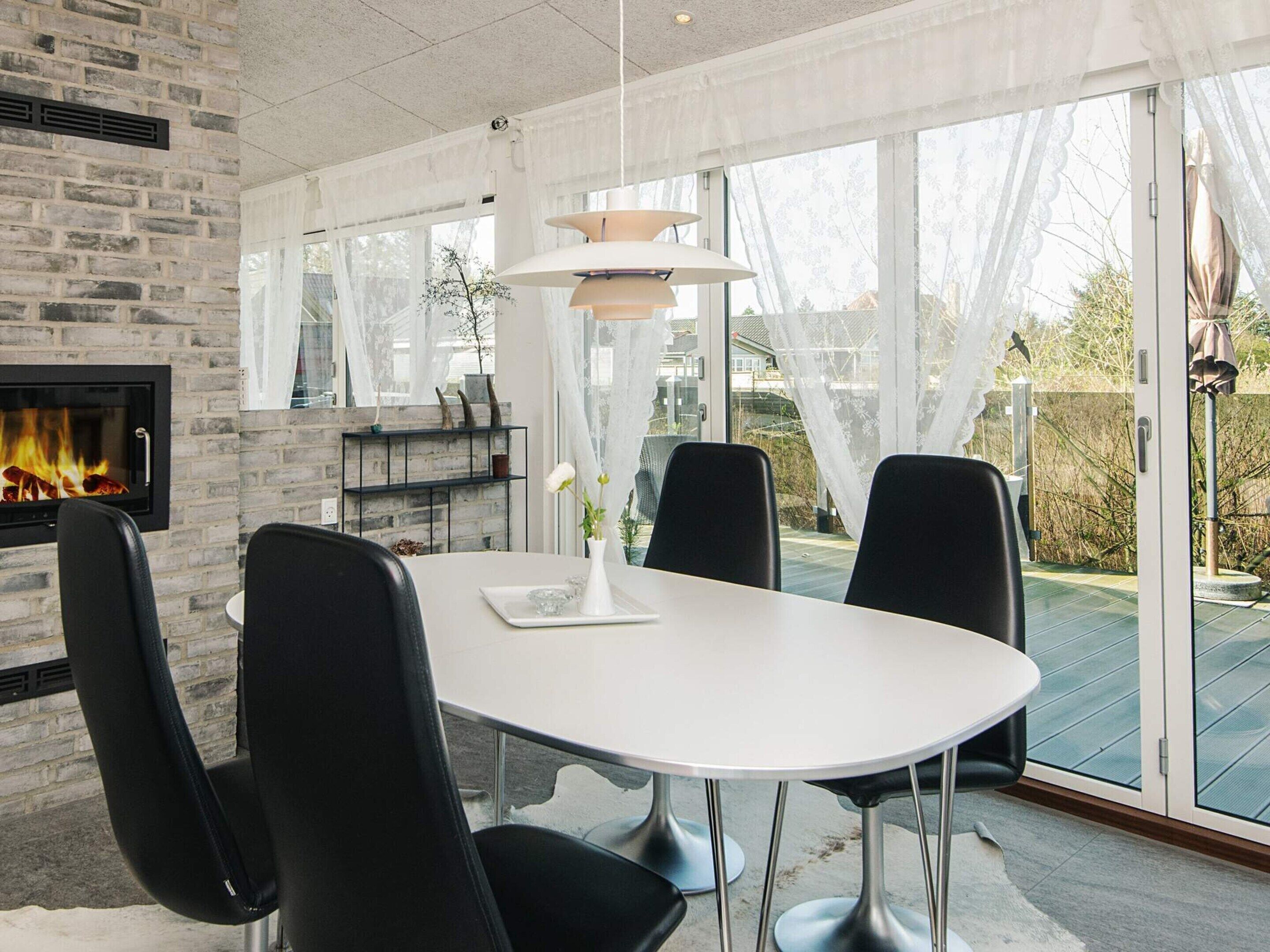 A modern dining area with a fireplace, a round table, and four chairs.