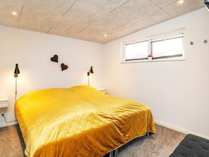 Ein Schlafzimmer mit einem großen Bett, zwei Wandlampen, einem Fenster mit Jalousien und einer Decke mit Einbuchtungslichtern.