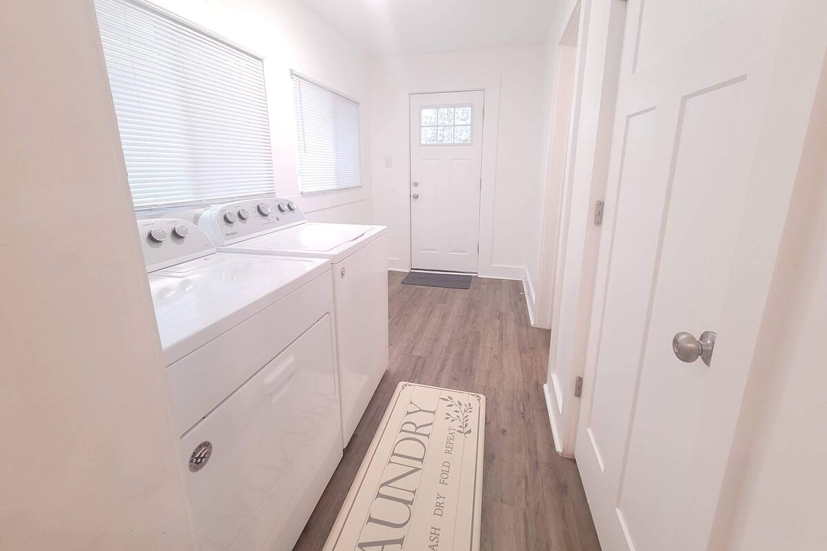 A laundry room with a washer and dryer, a door with a window, and a mat with 'laundry' written on it.