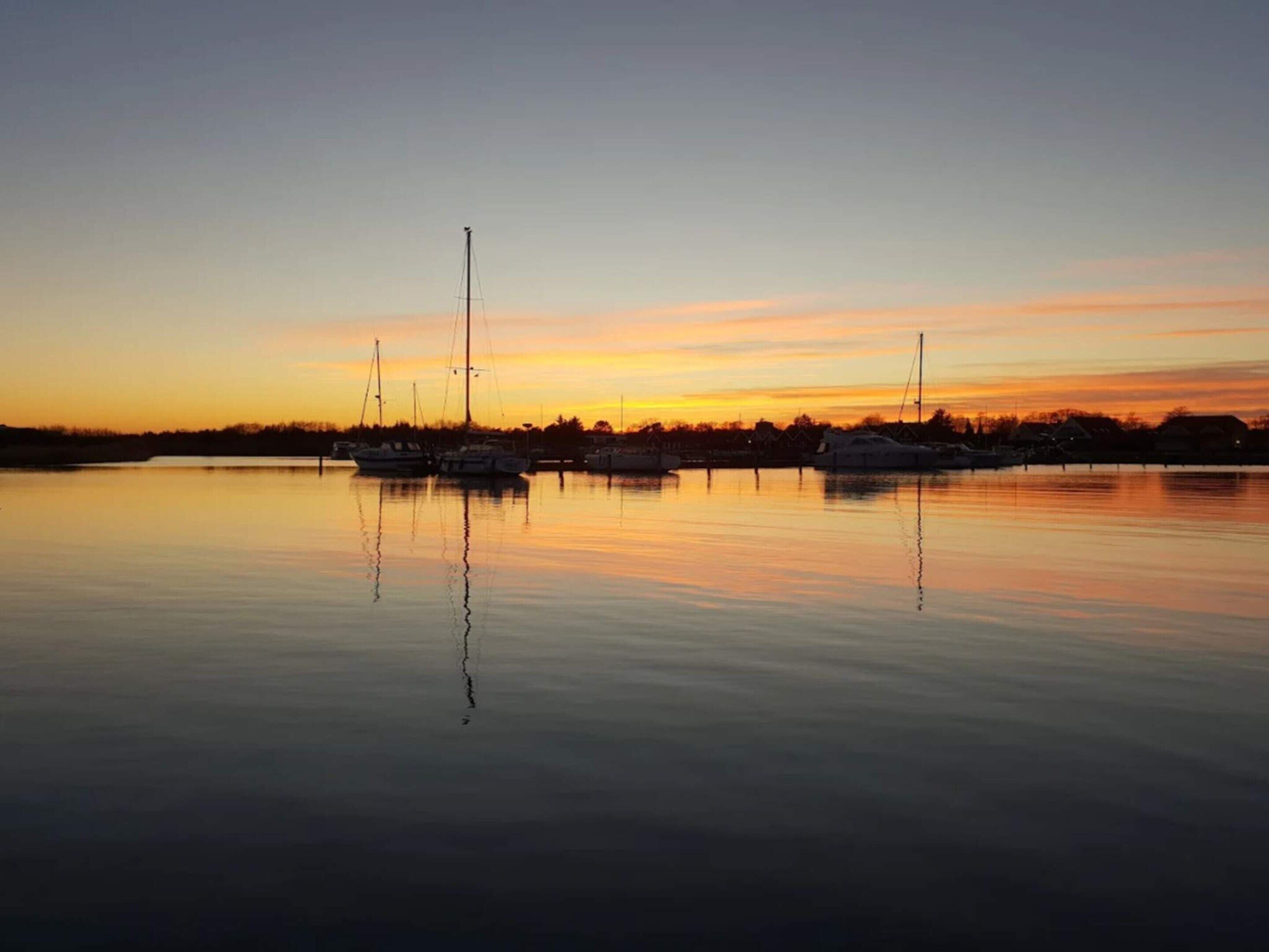 A marina at sunset with several sailboats docked.
