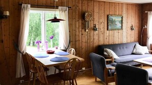 Et hyggeligt rum med trævægge, et spisebord med stole, en blå sofa og et billede på væggen.