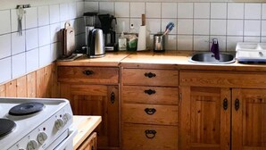 Et køkken med træskabe, komfur, vask og et vindue.