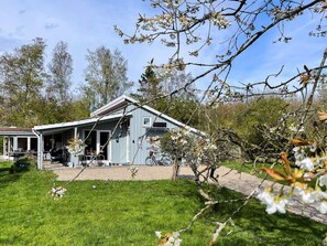 A single-story building with a covered porch, a bicycle parked outside, and a grassy lawn. - 10 Person Holiday Home in Dannemare (Dannemare)