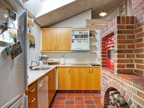 Una cocina con armarios de madera, horno empotrado y suelo de baldosas.
