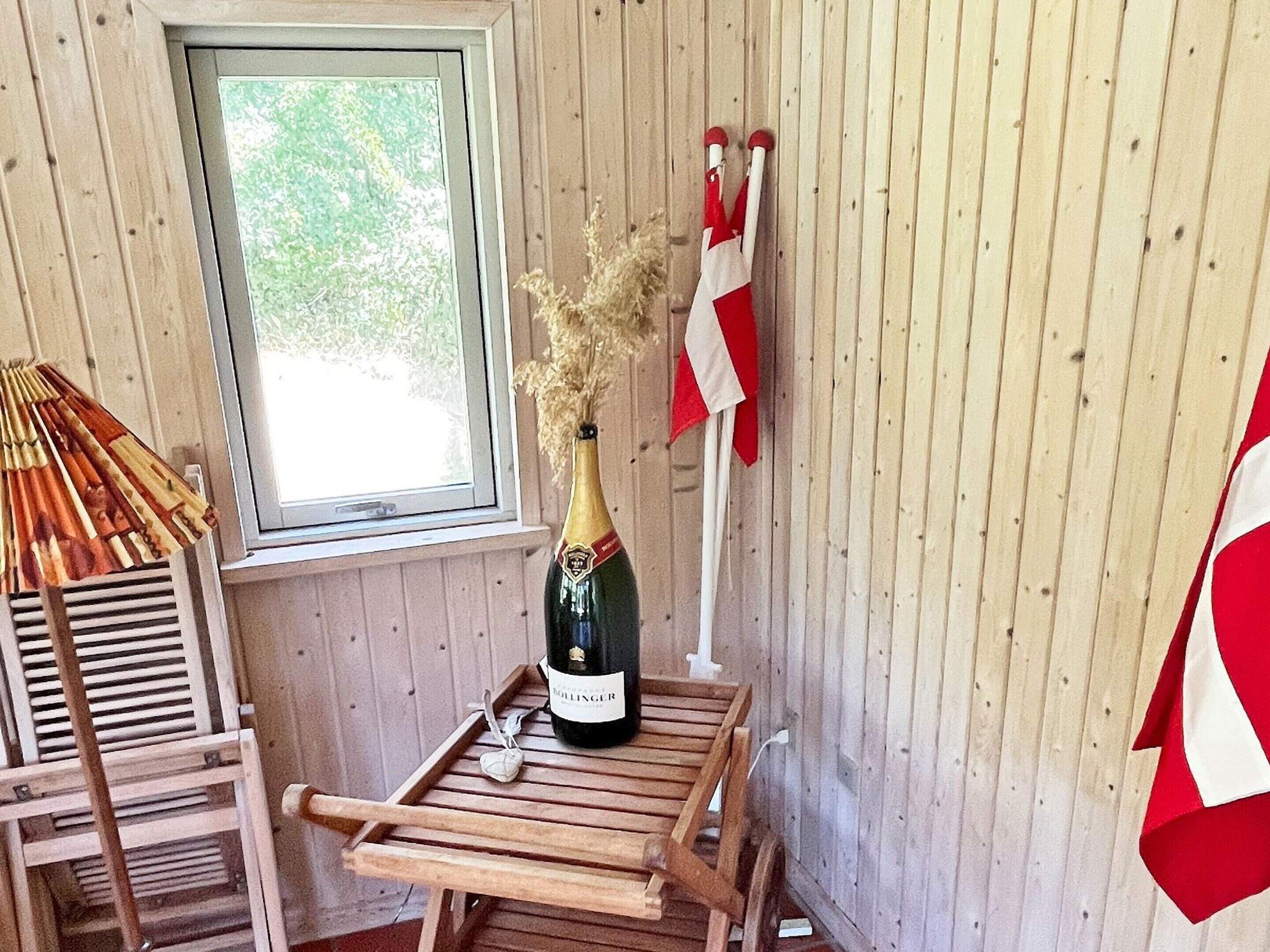 A wooden room with a window, a bottle of champagne, and a red and white flag.
