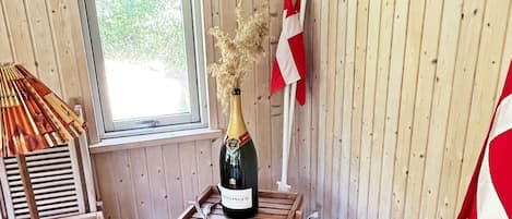 A wooden room with a window, a bottle of champagne, and a red and white flag.