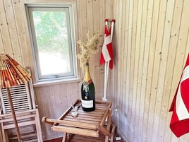 Una habitación de madera con ventana, una botella de champán y una bandera roja y blanca.
