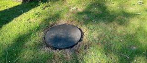 A circular hole in the ground surrounded by grass.