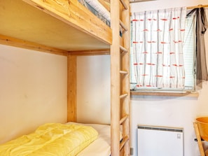A bunk bed with a yellow blanket, a window with curtains, and a wall-mounted air conditioner. - 10 Person Holiday Home in Dannemare (Dannemare)