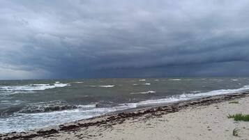 Una playa con mar agitado y cielo nublado.