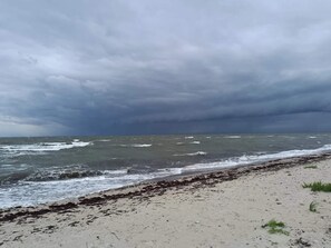 Una playa con mar agitado y cielo nublado.