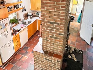 A kitchen with a brick wall, a refrigerator, and a sink. - 10 Person Holiday Home in Dannemare (Dannemare)