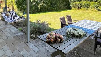 Eine Terrasse im Freien mit einem Holztisch, Stühlen und einer Hängematte.